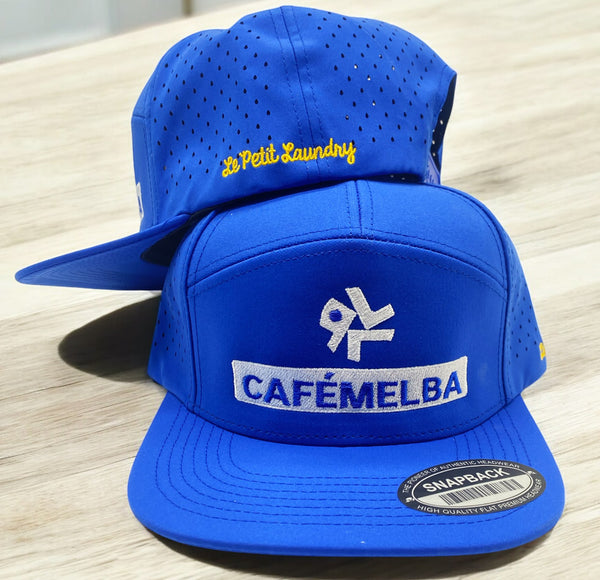 Blue snapback hat with Café Melba front logo and Le Petit Laundry back embroidery