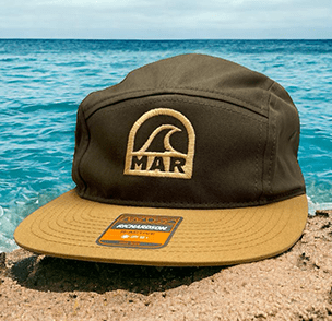 Brown and tan bucket hat with 'MAR' logo by the beach, Richardson tag.