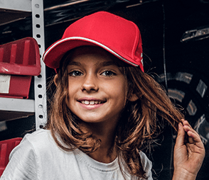 A little girl with a smily face wearing a red hat