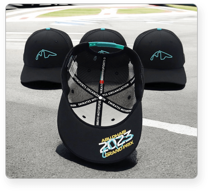 Black mesh caps with turquoise mountain logo, featuring 'Abu Dhabi 2023 Grand Prix' and 'Emirates Motorsports Organization' branding inside.