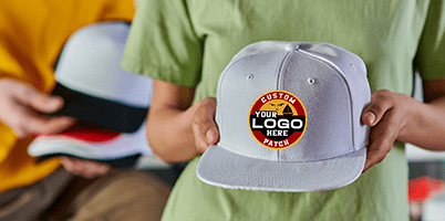 Person holding a gray hat with a custom logo patch.