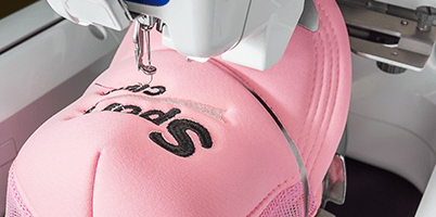 Pink hat being embroidered with 'Sport Club' logo.