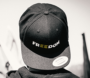 A closeup of a black snapback hat with a Freedom logo on it