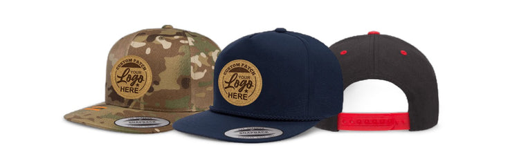 Three snapback hats displayed in a row: a camouflage hat with a custom patch, a navy blue hat with a blue bill, and a grey hat with a red snap closure. Each features a logo patch space.