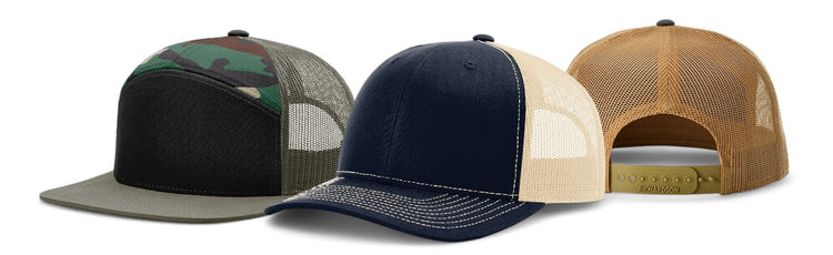 Three trucker hats with mesh backs in camo, navy, and tan, featuring adjustable snap closures