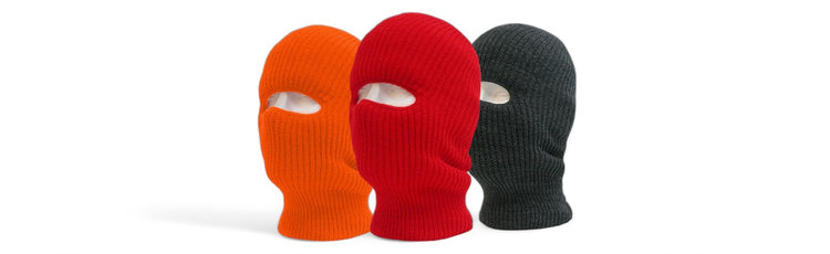 Three knitted ski masks in orange, red, and dark gray, each covering the full face except for the eyes