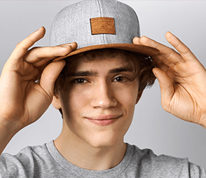 A teenager is wearing a grey and brown 5-panel hat.