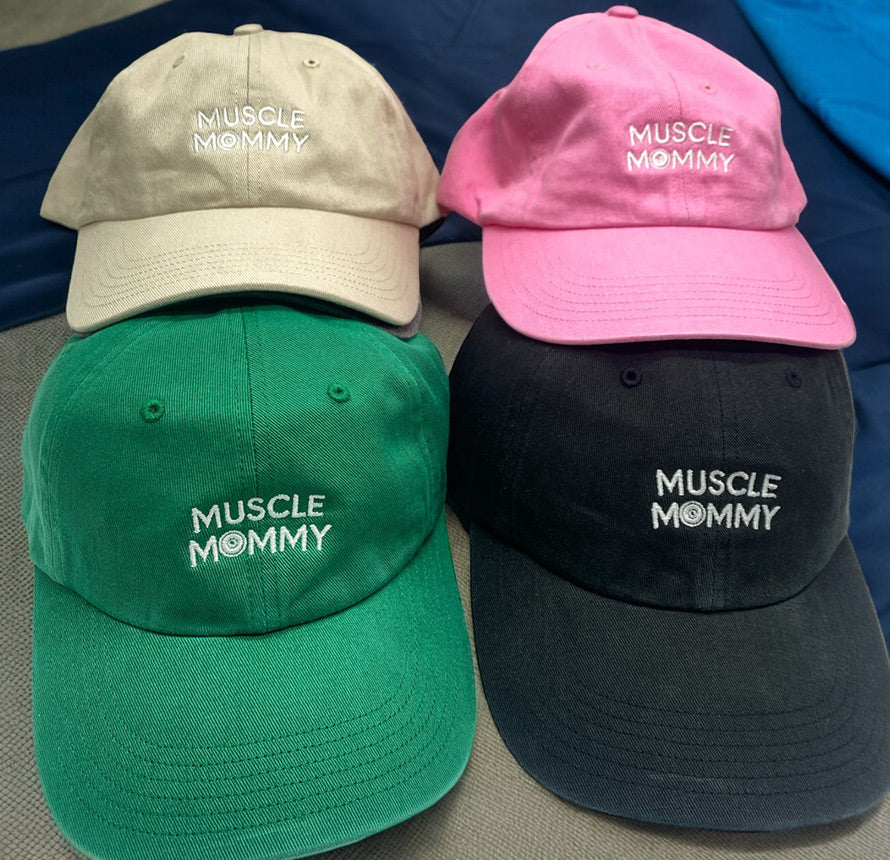 Four 'Muscle Mommy' hats in beige, pink, green, and black.