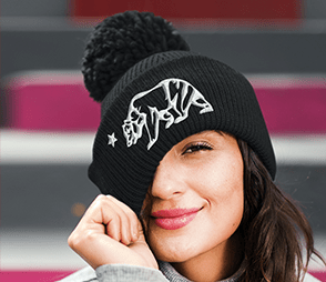 A girl is wearing a black beanie with a white bear sticker on it.