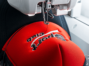 Embroidery machine stitching a red cap.