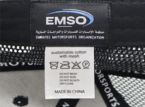 Close-up of a private label tag for 'Emirates Motorsports Organization' (EMSO), featuring a sustainable cotton material with care instructions and a 'Made in China' note.