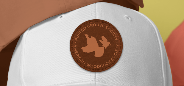 White Cap with etched brown leather patch for 'Ruffed Grouse Society' and 'American Woodcock Society' with bird imagery.