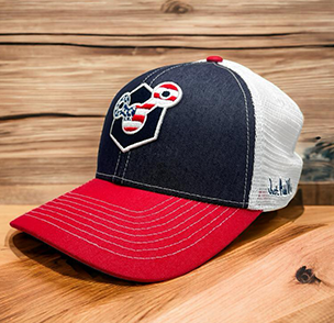 Navy and red trucker cap with skull and spatulas logo, wood backdrop, 'Chef's In Training' text.