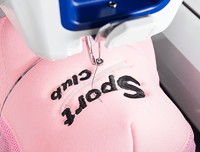 A closeup of a pink hat under embroidery machine