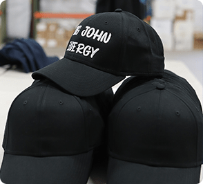 Black baseball caps with _St. John Energy_ text, side by side on a table