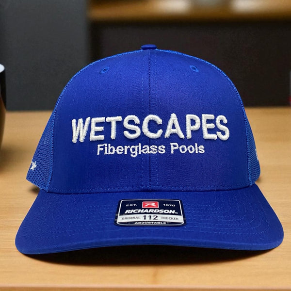 Blue Richardson 112 trucker hat with embroidered Wetscapes Fiberglass Pools logo in white thread.