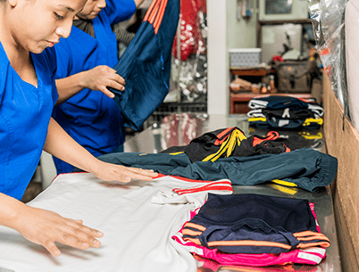Two workers folding clothes at a textile distribution center.